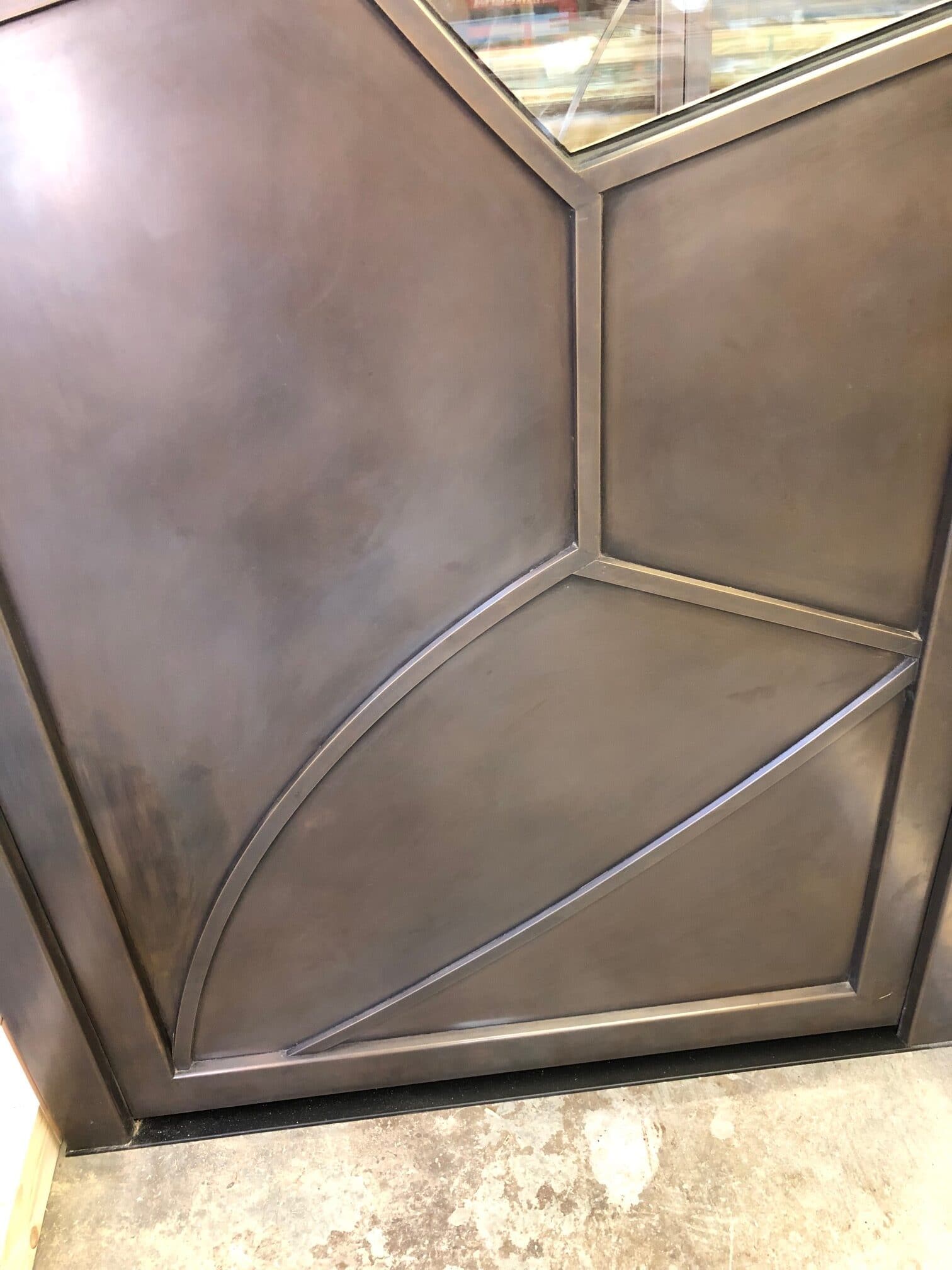 Bronze patinas on the entry door panels with bent divided lite