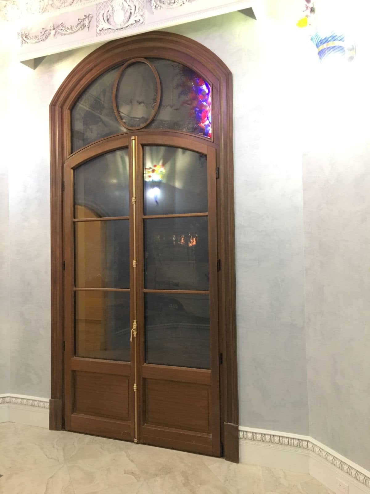 Porte-fenêtre cintrée en acajou avec jour ovale dans l’imposte