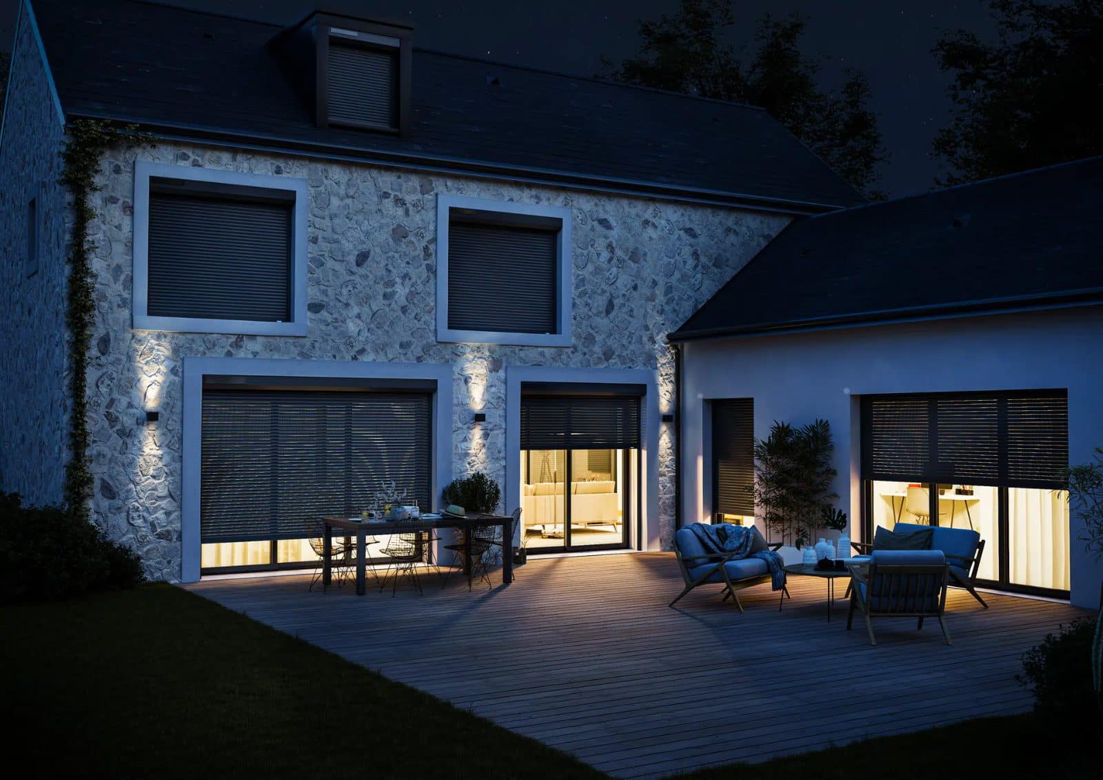 Maison en pierre la nuit avec volets roulants à demi fermés, lumière à travers les fentes