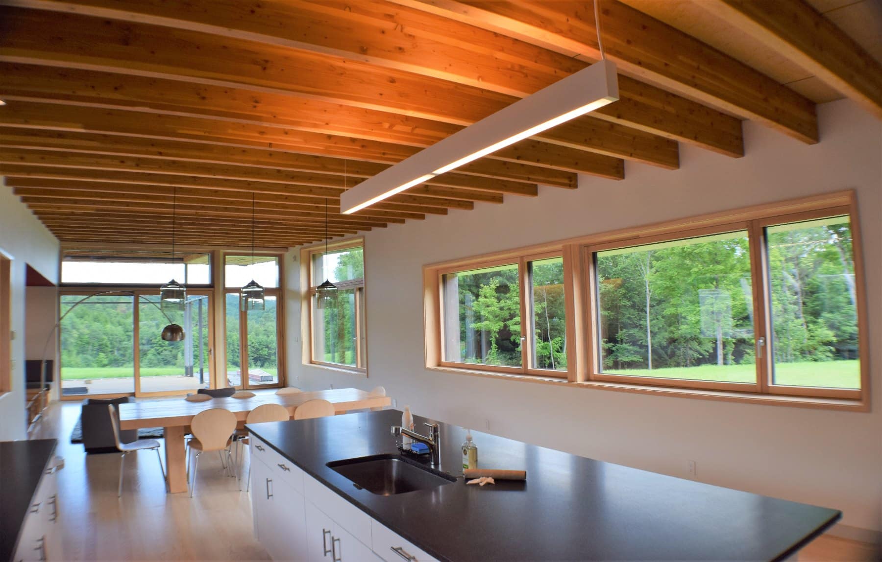 Bandeau de fenêtres en bois le long d’une cuisine contemporaine au plafond en bois apparent