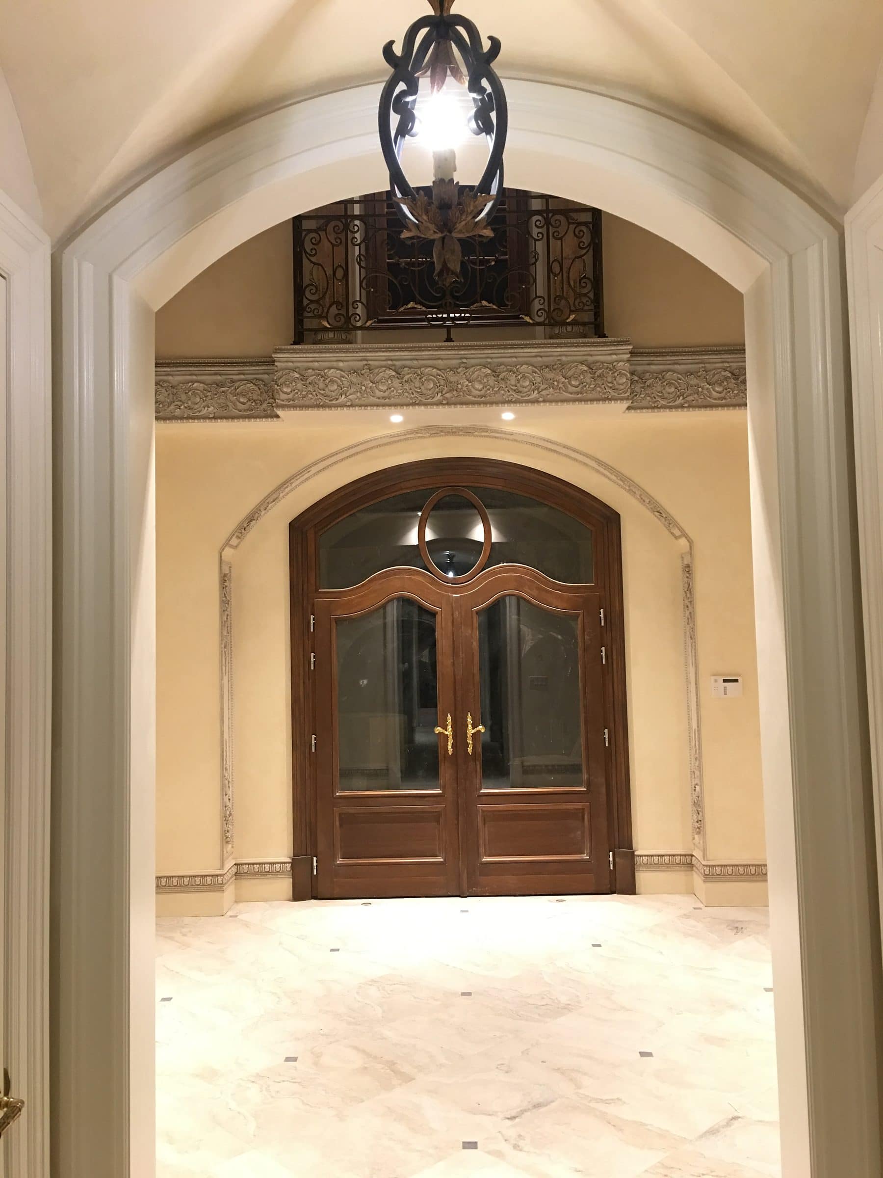 Porte d’entrée double cintrée en bois au fond d’un grand hall