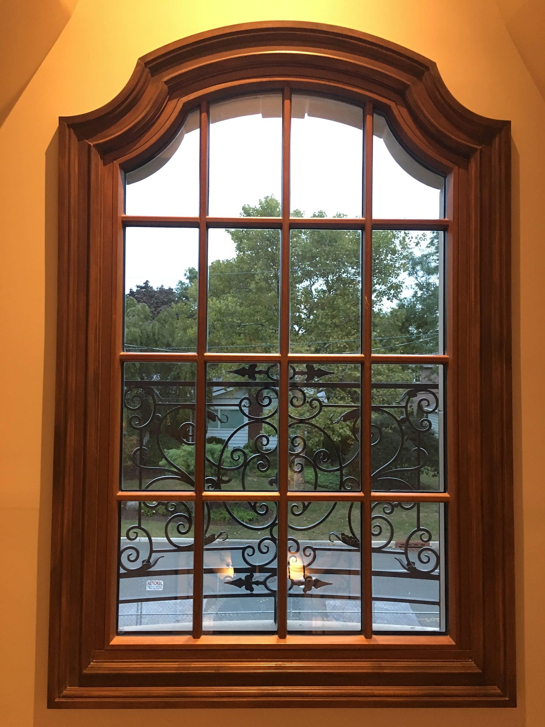 Tall mahogany French casement window with true divided lites opening onto a wrought iron Juliet balcony