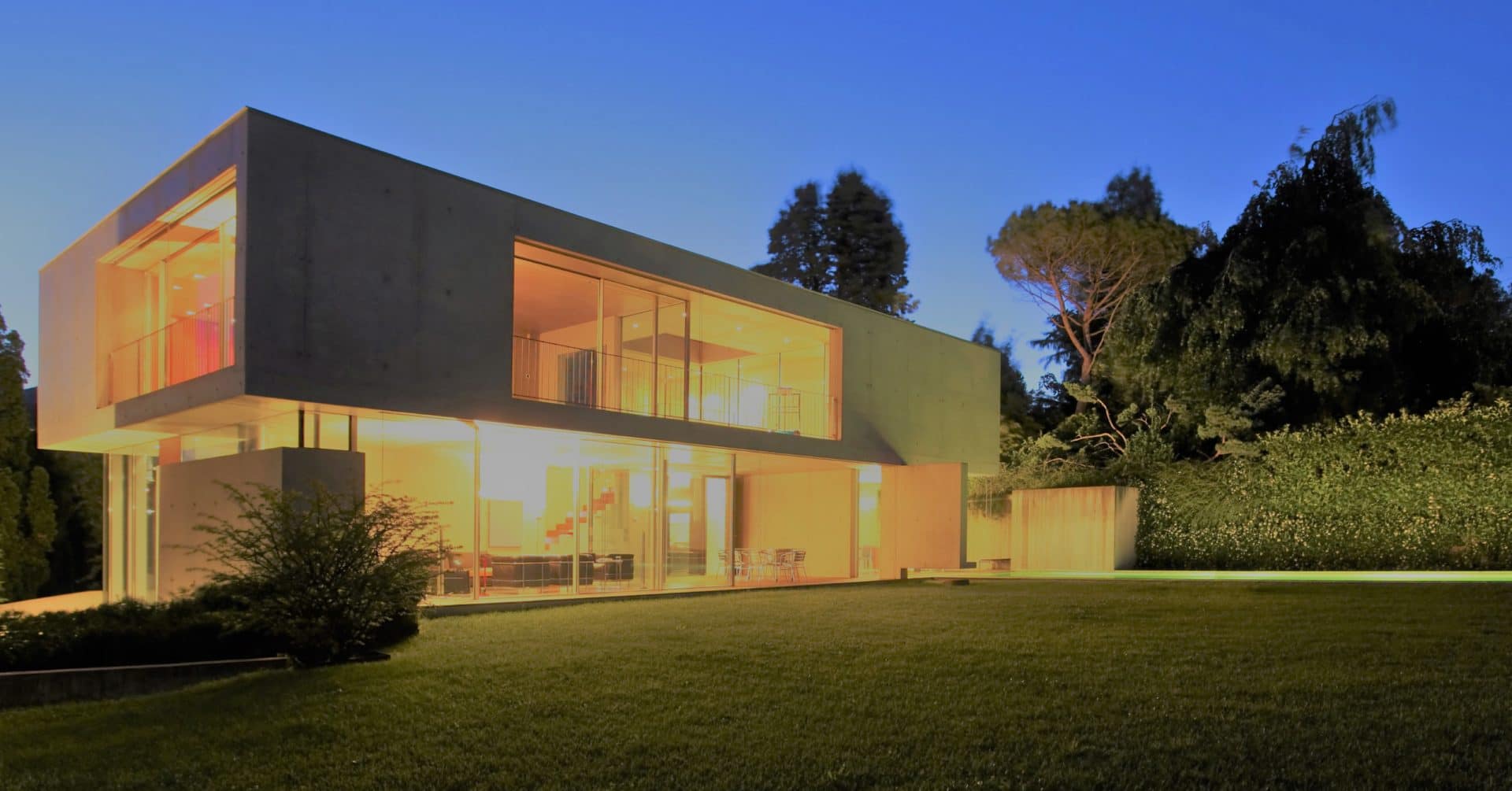 Résidence contemporaine de nuit avec de grandes baies vitrées