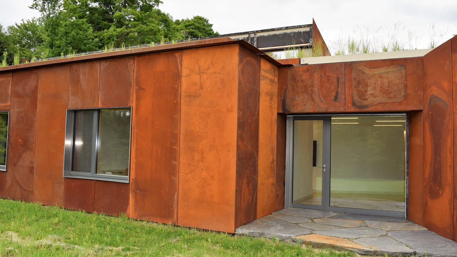Maison contemporaine à façade en acier autopatinable, grandes fenêtres bois-aluminium et porte vitrée