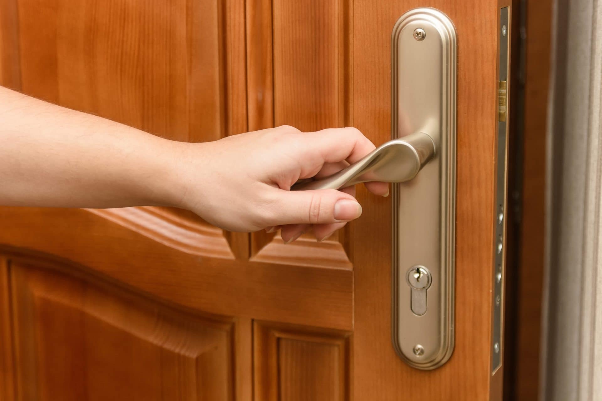 Main sur la béquille d’une porte d’entrée en bois à panneaux moulurés