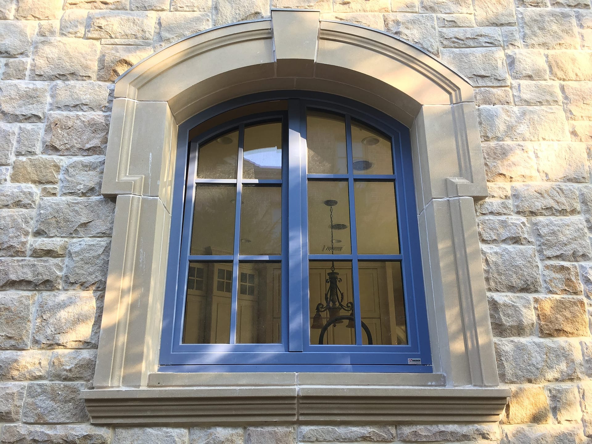 Arched French casement window in a limestone facade, French chateau style home