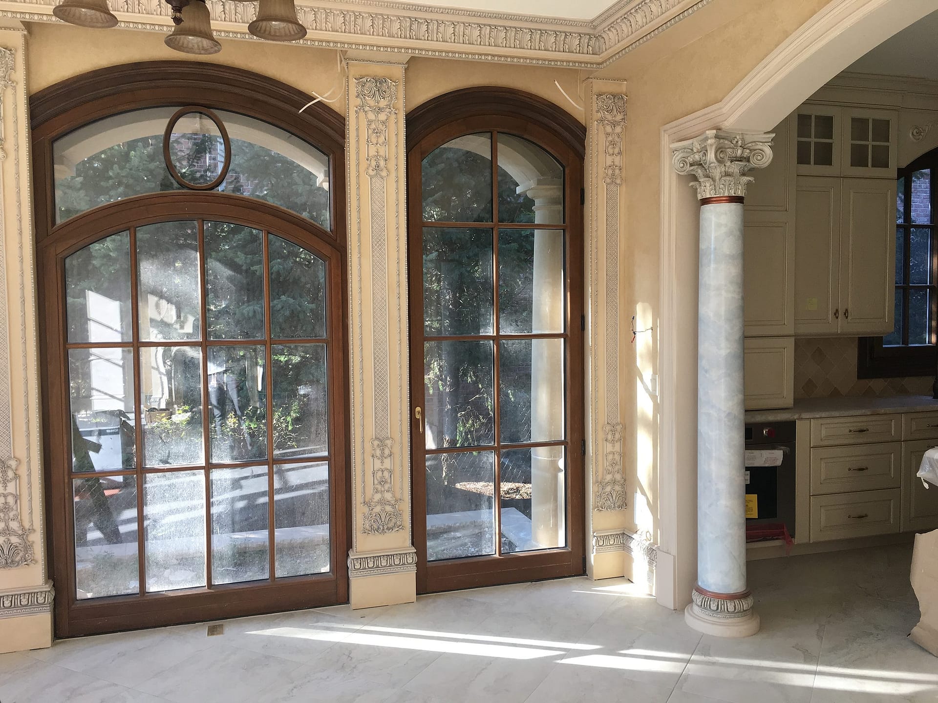 Porte-fenêtre et fenêtre cintrées en acajou à petits bois entre des pilastres sculptés